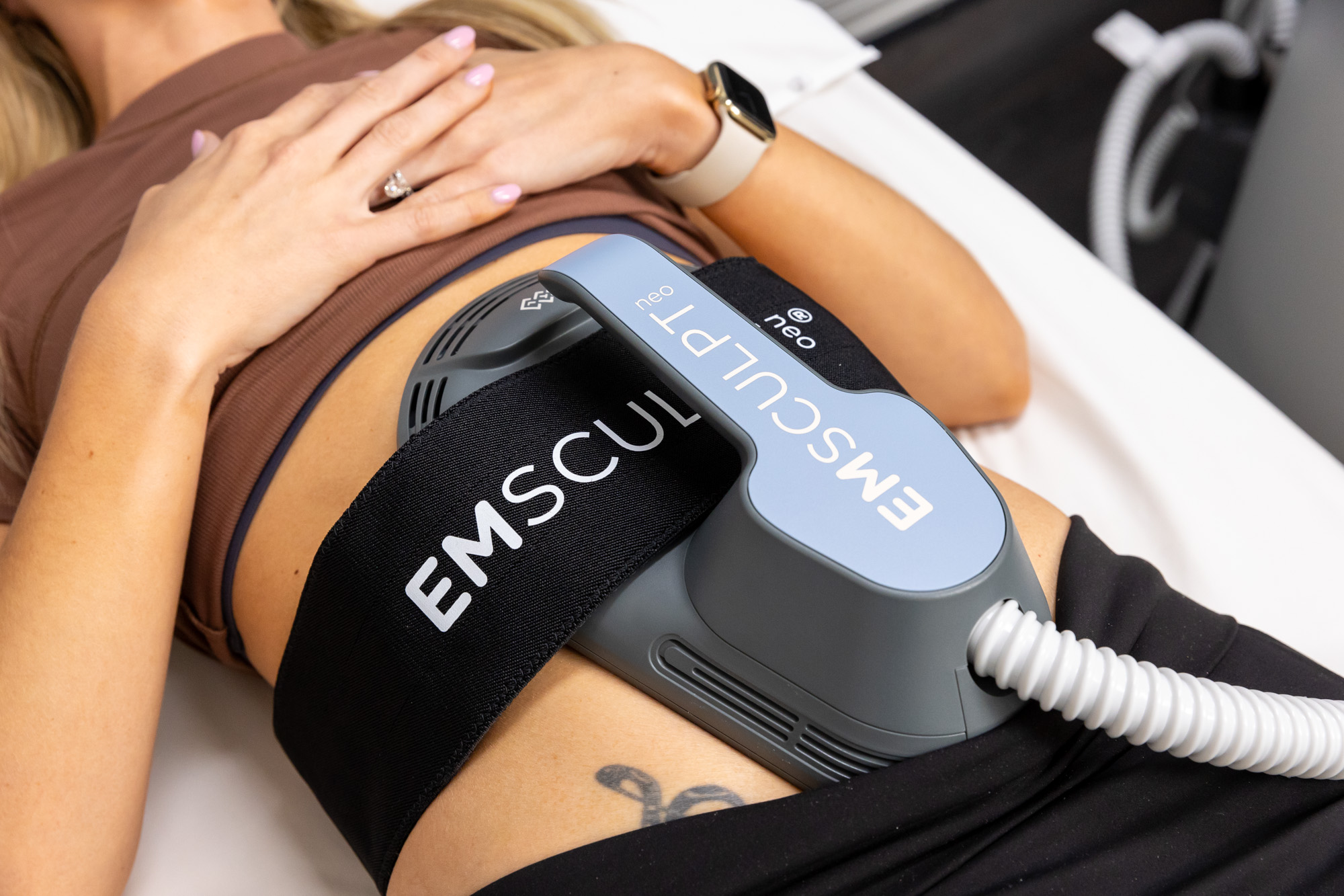 Close-up of an Emsculpt NEO device on a patient's abdomen, reflecting body contouring in Arlington.