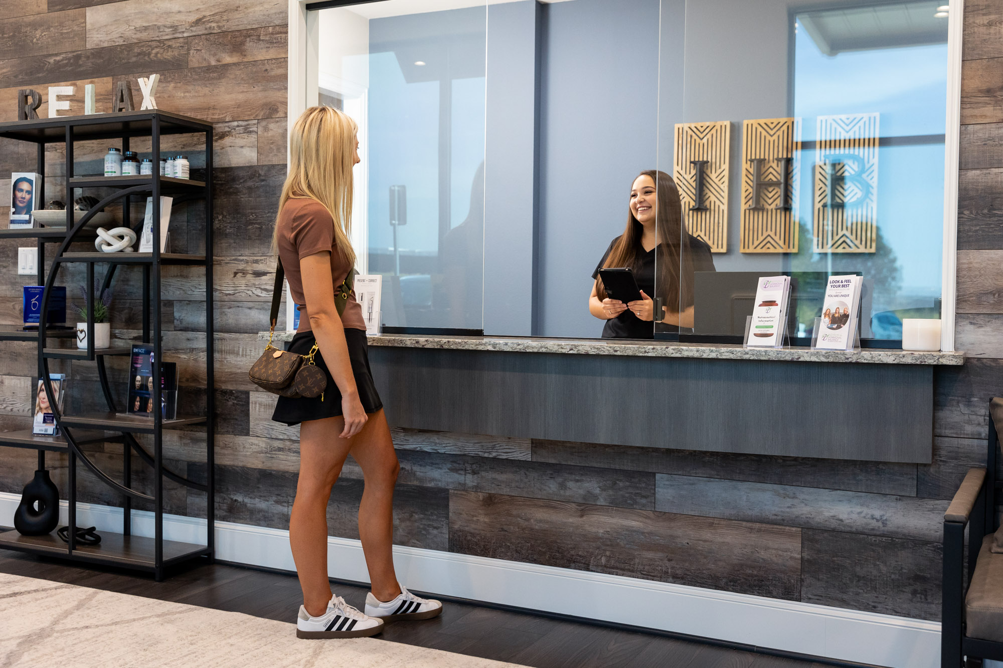 A patient speaks with a provider at the front desk of the Institute for Hormonal Balance as she walks in for her consultation for laser skin resurfacing in Arlington.