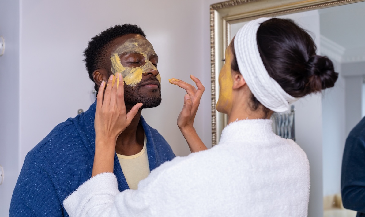 A woman rubs nourishing ingredients into a man's face for complete skin care in Arlington.