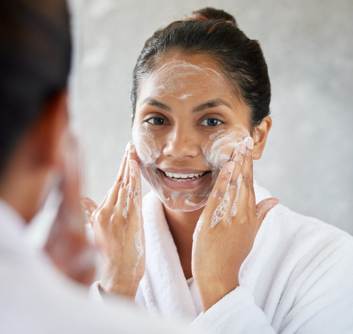 A woman happily enjoys a gentle cleansing formula for her skin care in Arlington.