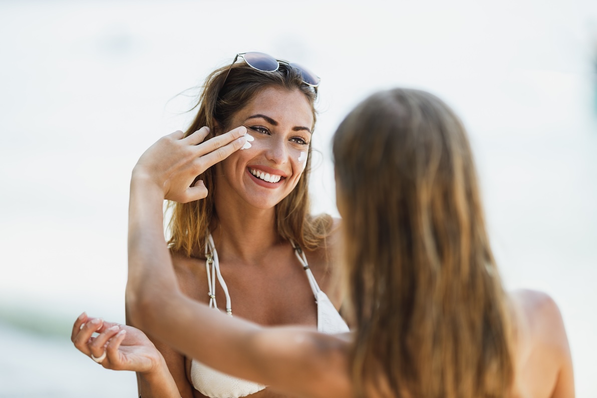 A daughter rubs sunscreen on her mom's face as a necessary part of skin care in Arlington.