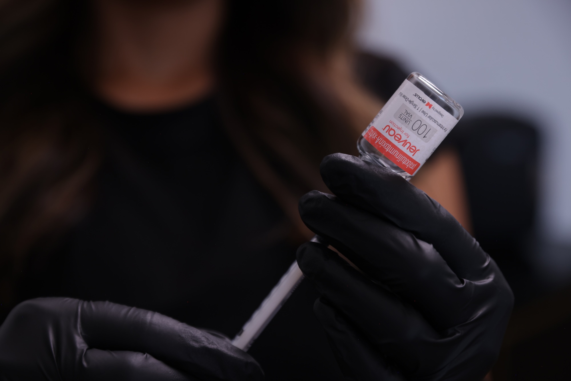 A close-up of a provider using a syringe to take product out of a vial of Jeuveau.