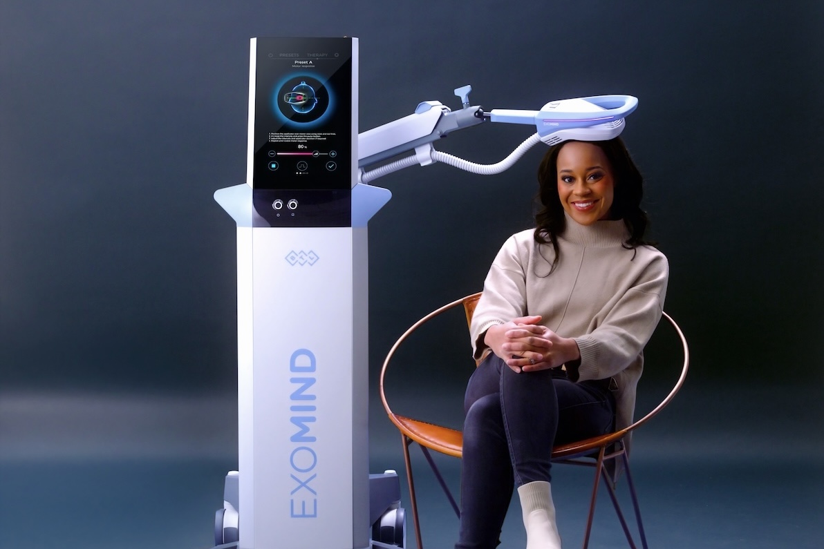 A female patient sits comfortably as she receives medical TMS in Arlington with the EXOMIND device.