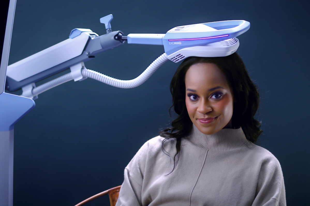 A woman smiles as she receives EXOMIND, a transmagnetic therapy in Arlington.